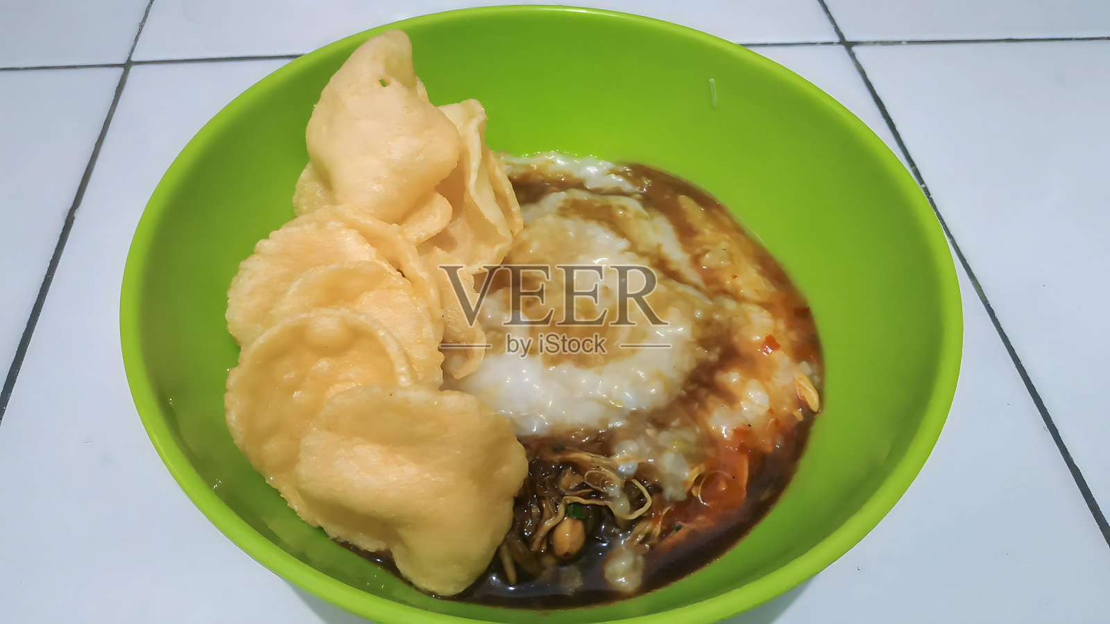 Bubur ayam:一碗有饼干、辣椒酱和酱油的早餐照片摄影图片