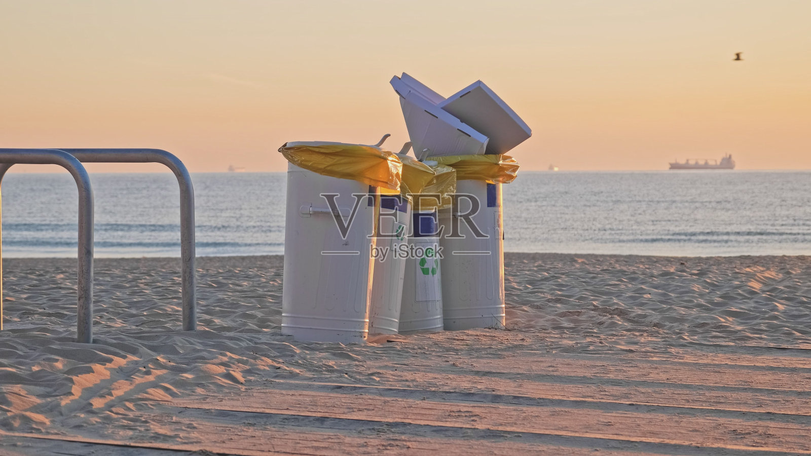 在海滩通宵派对后堆满垃圾的金属垃圾箱照片摄影图片