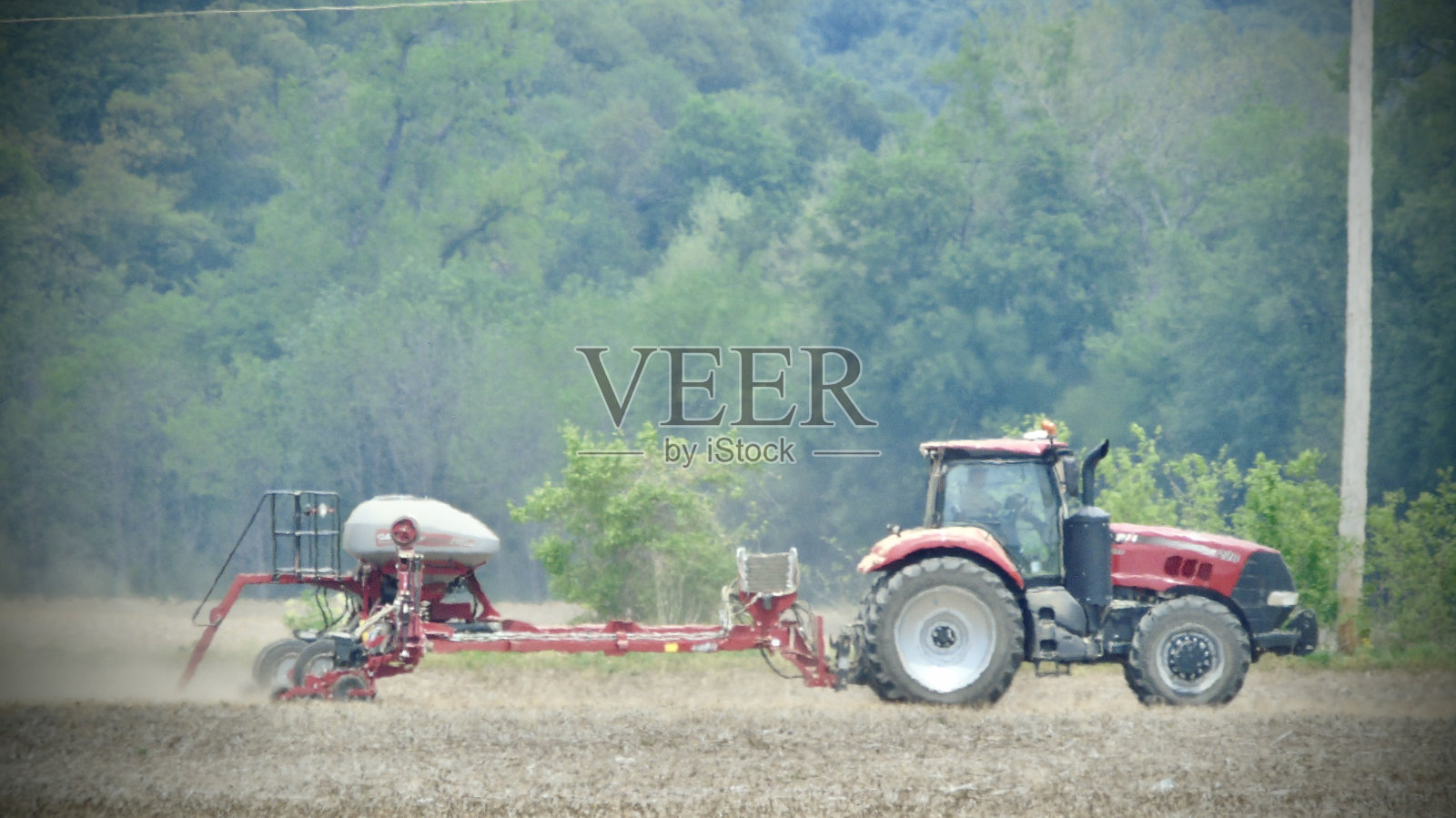 在春季播种季节之前，一位农民开着红色农用拖拉机整理田地。照片摄影图片