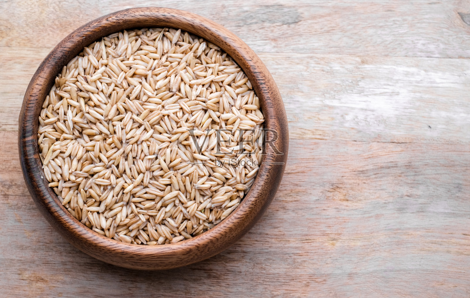 燕麦种子在木制背景上的木制盘子顶部视图。特写镜头的种子照片摄影图片