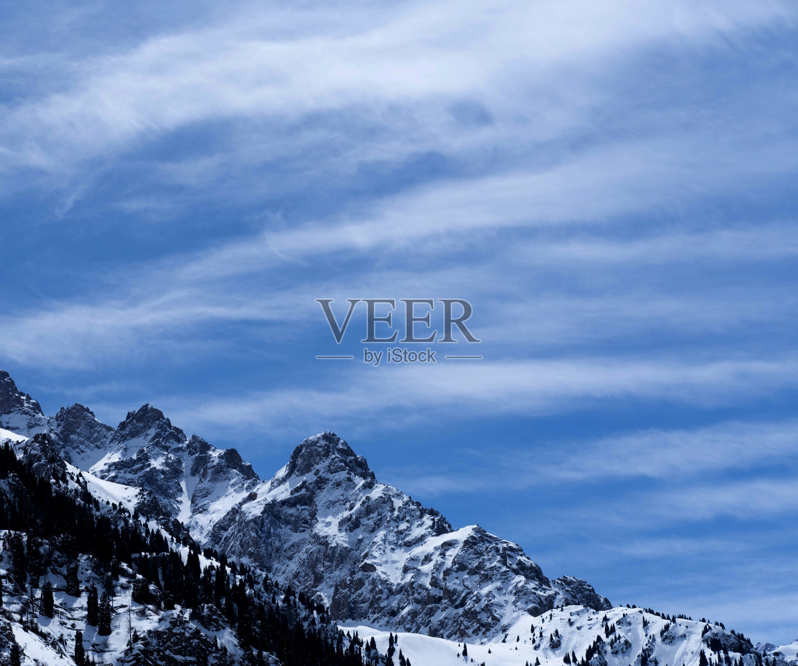 冬天的风景。哈萨克斯坦的高山被白雪覆盖，映衬着蓝天。照片摄影图片