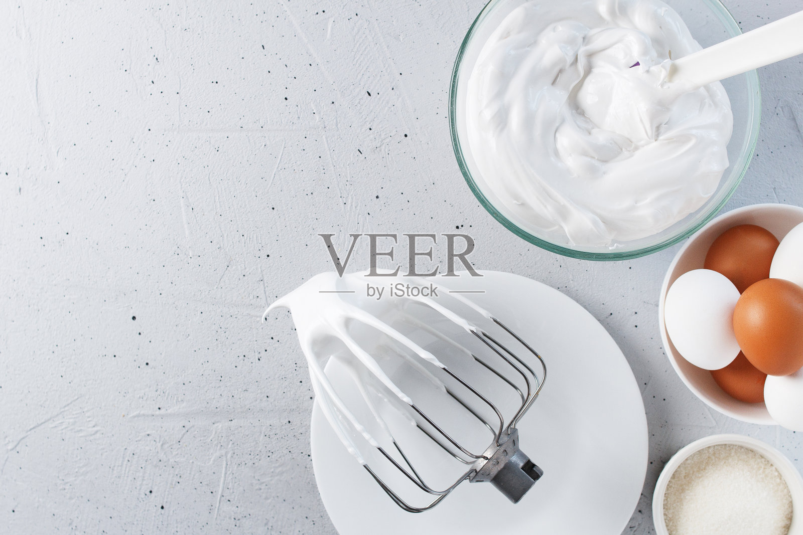 搅打的蛋白——搅打的意大利蛋白霜，鸡蛋，糖，在灰色背景上。副本的空间。照片摄影图片