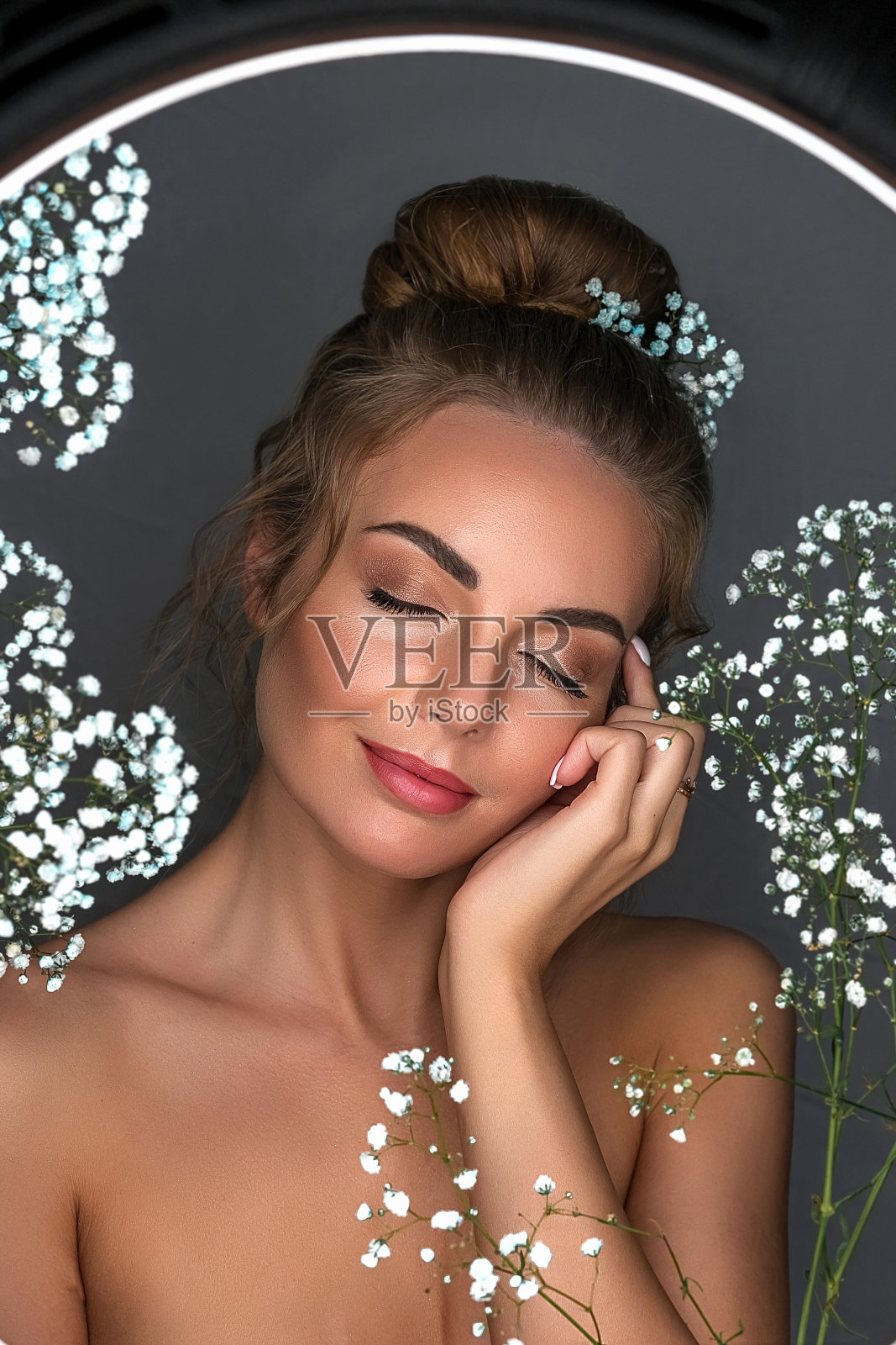 肖像一个微笑的美丽，甜美的女孩在灰色的背景与白色的花朵。照片摄影图片