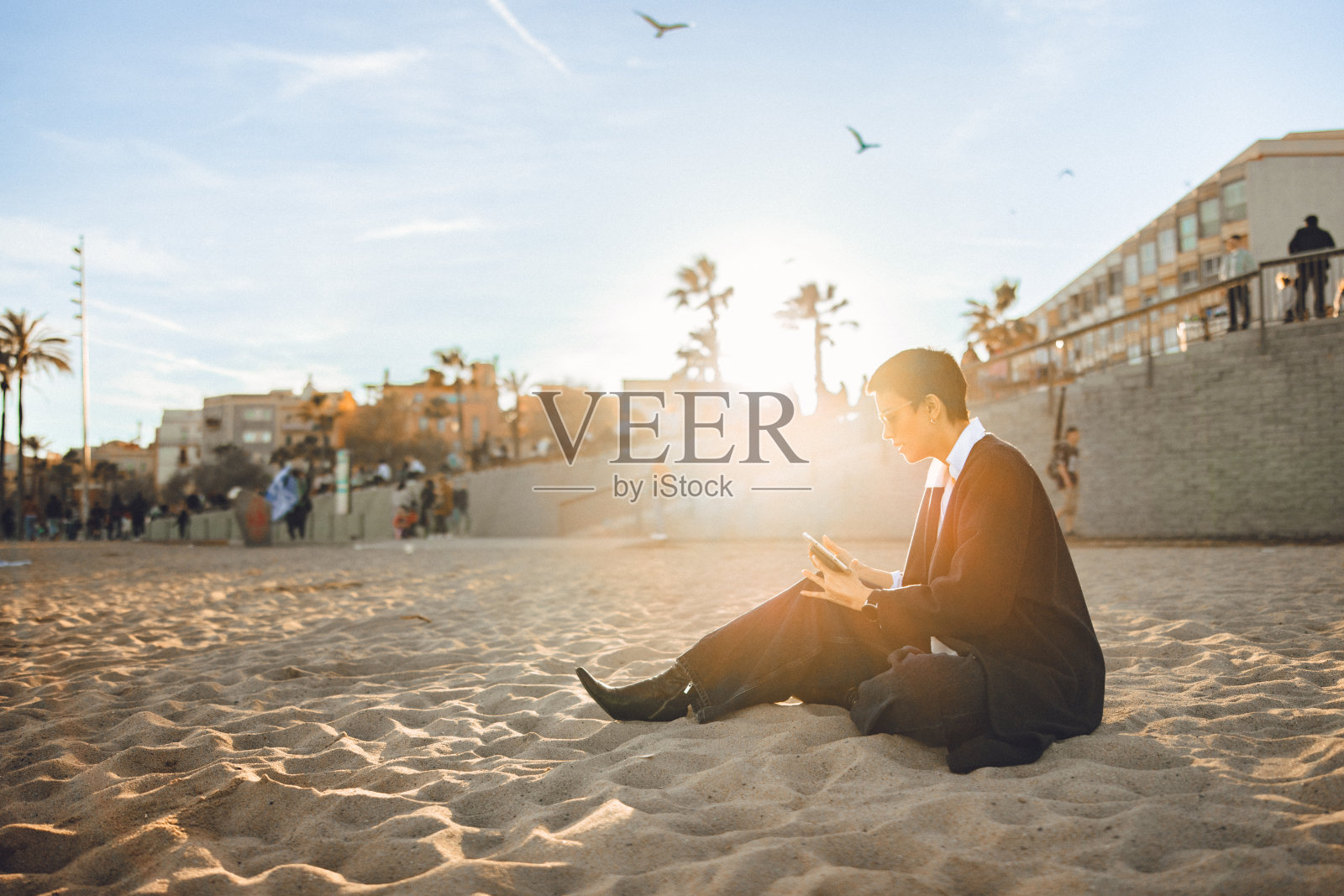 年轻女子在城市海滩用手机看小溪照片摄影图片