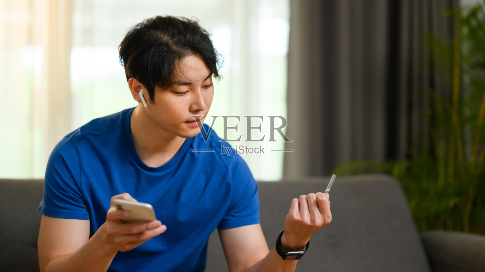 穿着便服的男子手持信用卡，用智能手机通过互联网或网上支付订单。照片摄影图片