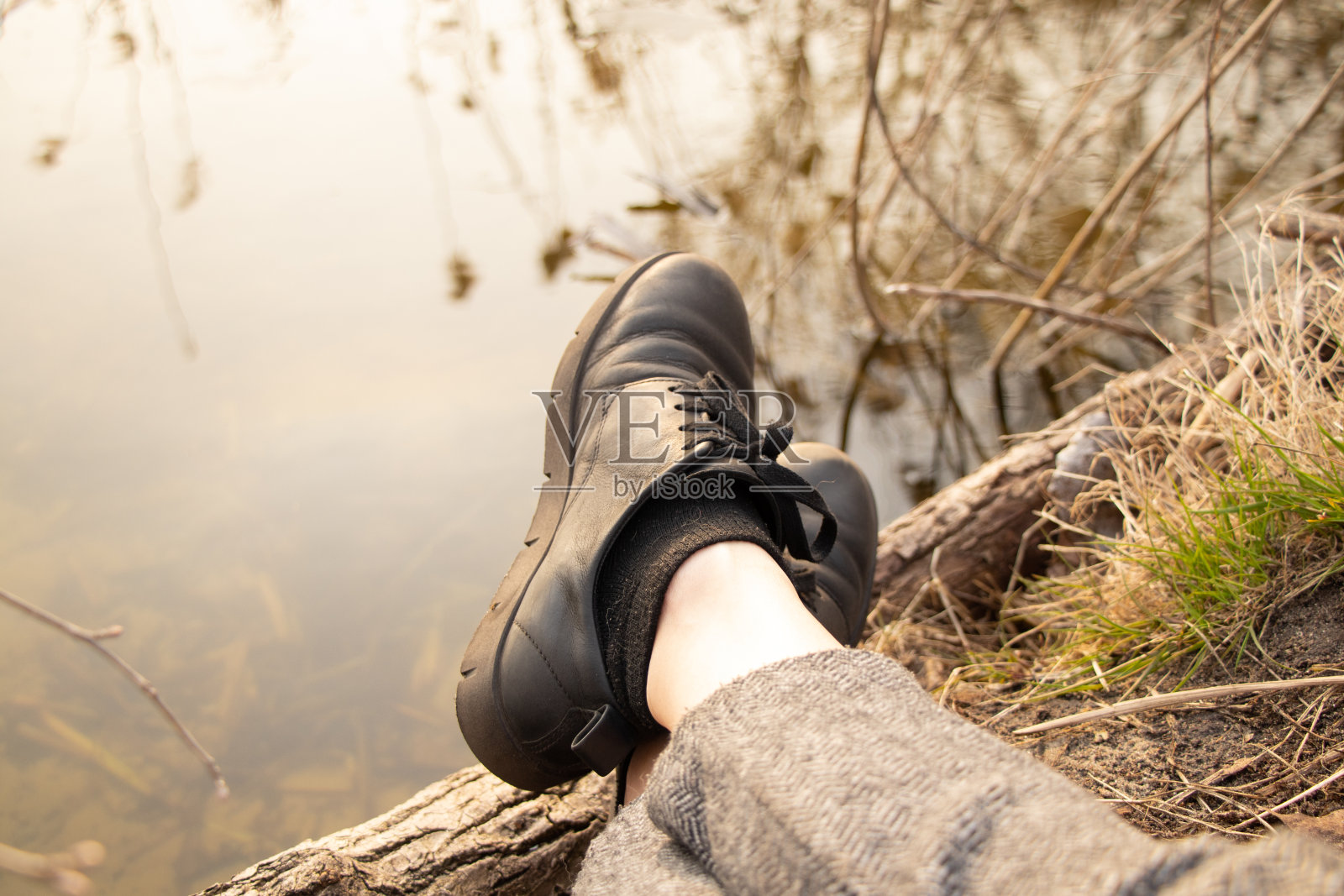 女性腿上的黑色皮鞋背景是春日里在森林里度假的小河，户外照片摄影图片