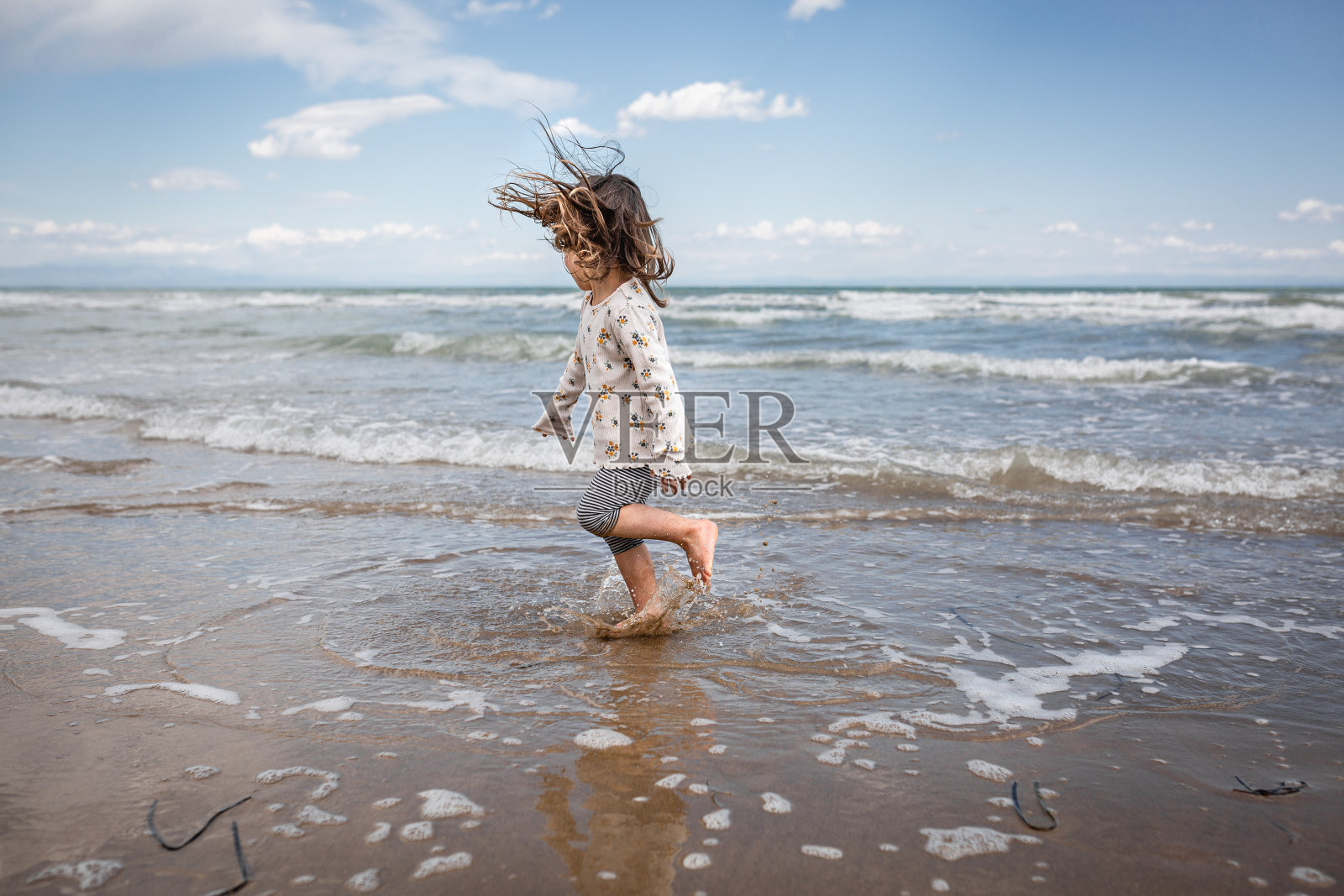 跳舞的小女孩，吹着头发，玩弄着波浪照片摄影图片