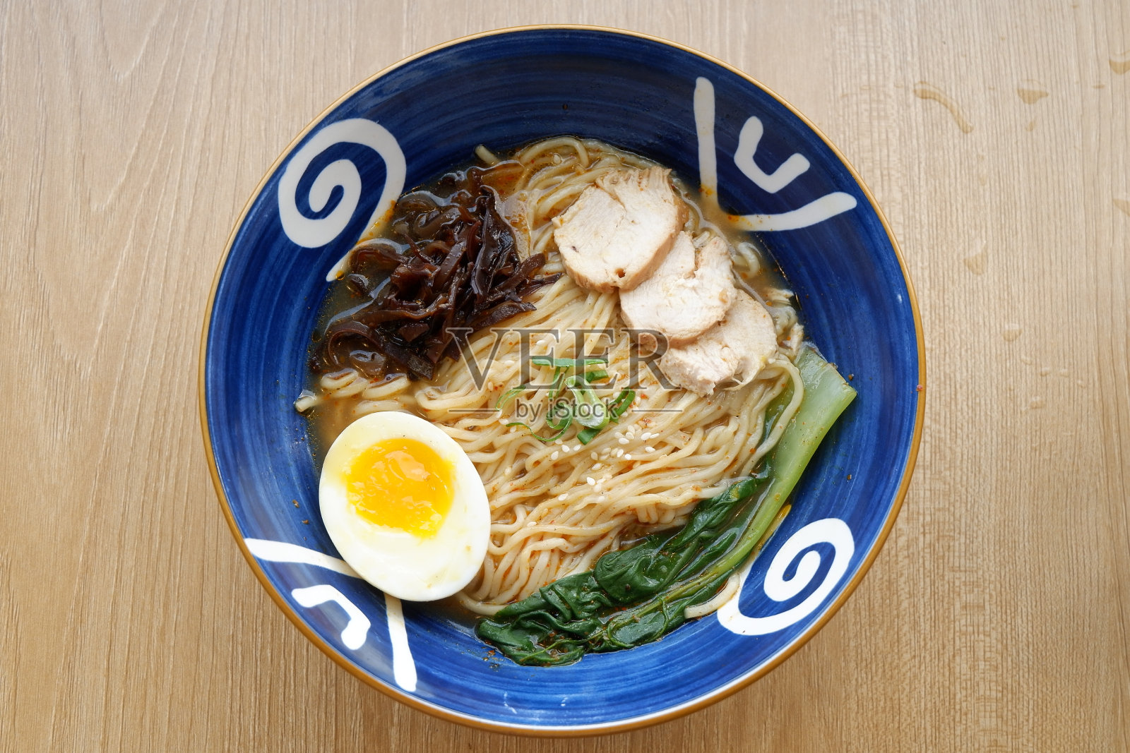 一碗盛满面条的碗，上面放着炸鸡片、蘑菇、煮鸡蛋和蔬菜照片摄影图片