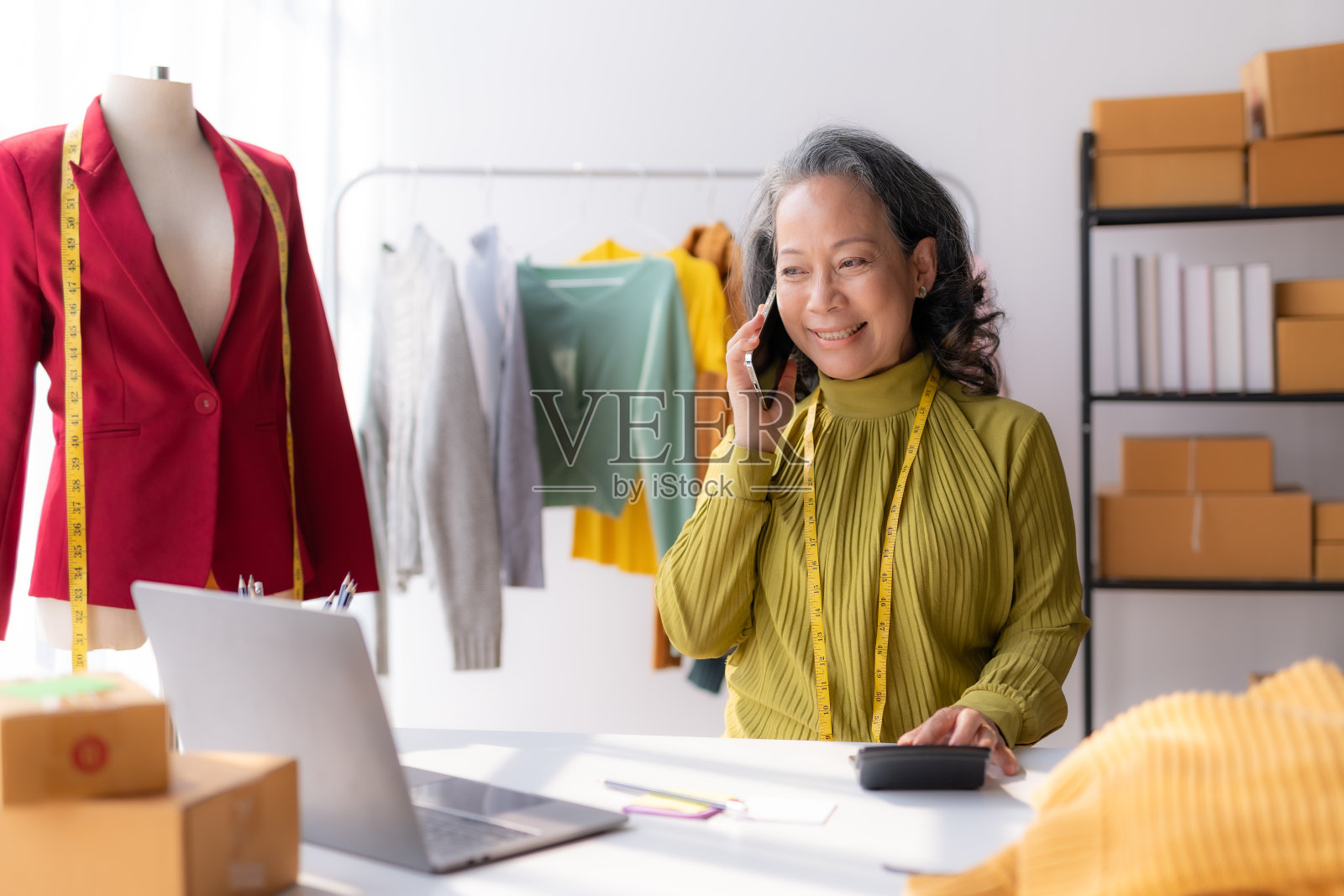 资深亚洲设计师在电话中与客户讨论剪裁和编辑。照片摄影图片