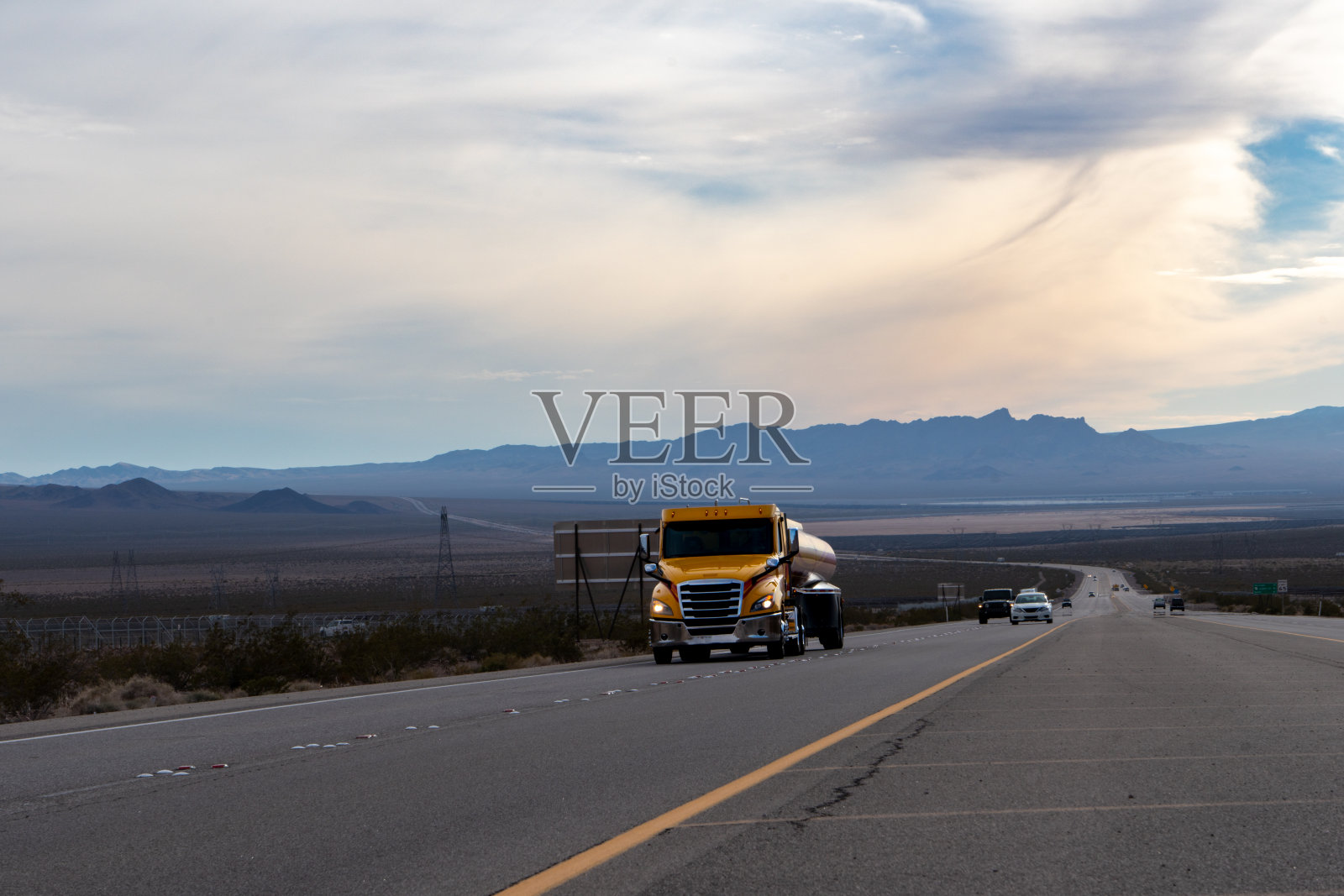 一辆强大的半挂车穿过干旱的沙漠，在路上踢起了沙子的漩涡。它气势磅礴的存在支配着贫瘠的景观，因为它在无情的地形中坚定地巡游。照片摄影图片