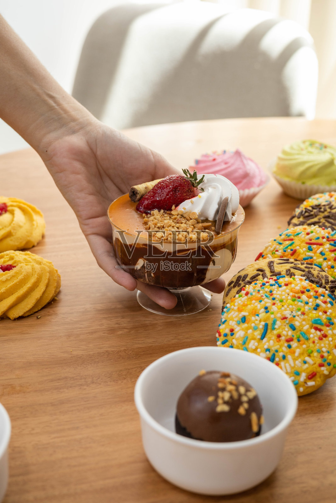 上菜桌上摆着精美的甜点，其中有冰淇淋杯、草莓奶油、粥状饼干照片摄影图片