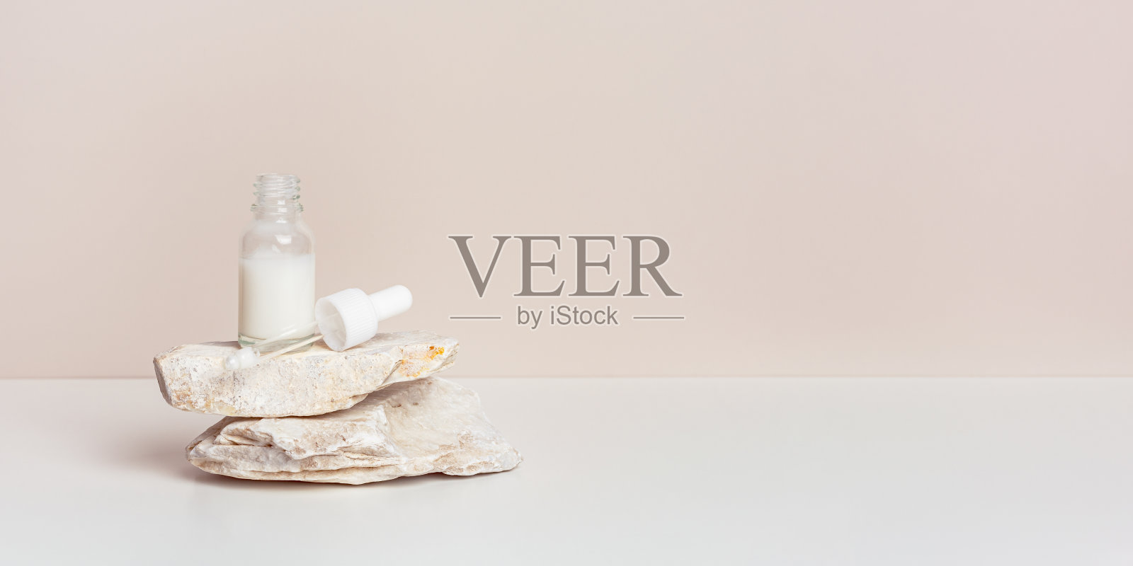 玻璃滴管瓶与白色血清或奶油站在天然石材，米色粉彩背景，横幅与复制空间。天然有机Spa化妆品，极简风格，化妆护肤品照片摄影图片