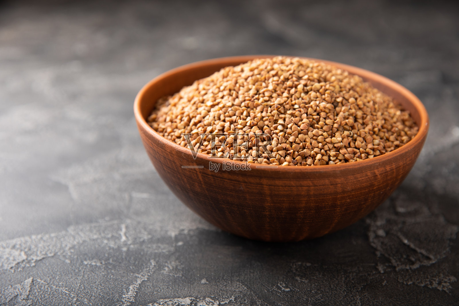 黑色大理石背景上的碗里装着荞麦。生荞麦。无谷蛋白粥的配料。健康食品。复制的地方。照片摄影图片