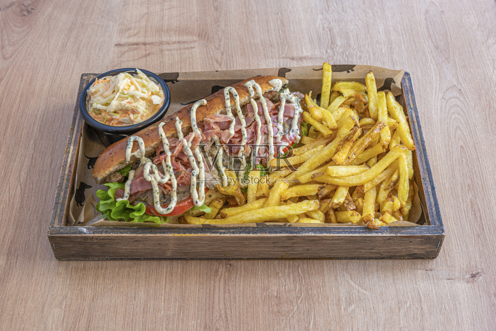 木托盘里有咖喱热狗、烤火腿、酱汁、西红柿和生菜，还有薯条凉拌卷心菜照片摄影图片