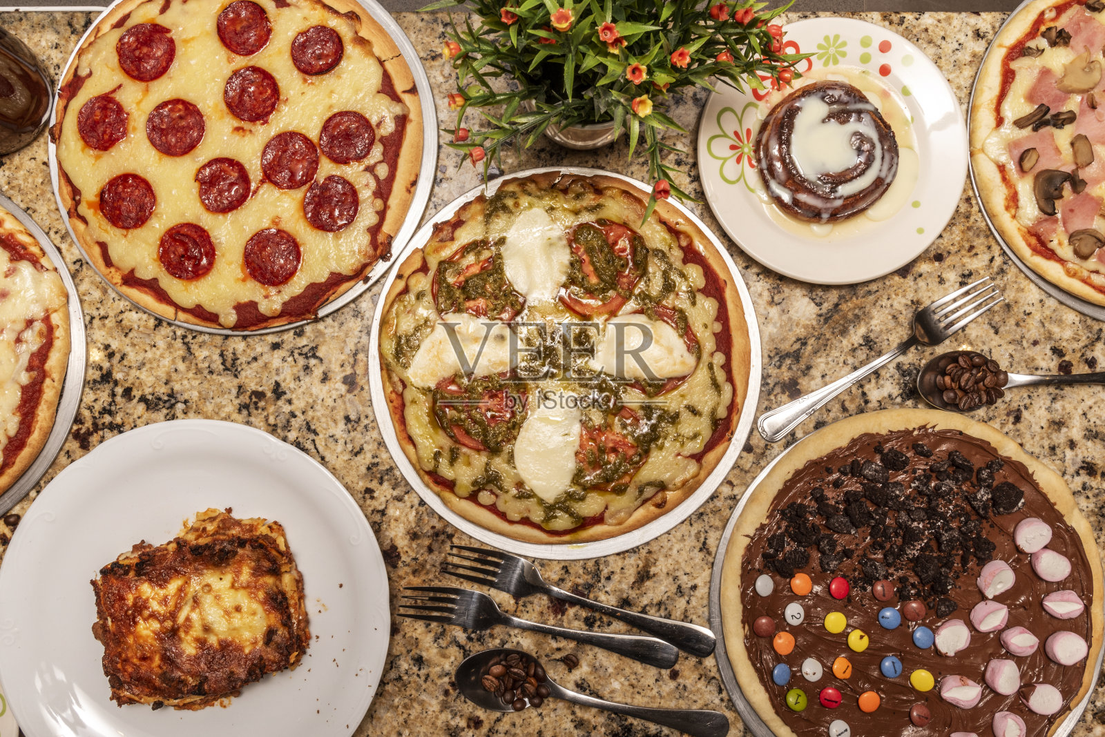 一套快餐菜肴，主要是什式，意大利辣肠，奶酪和番茄披萨，委内瑞拉甜点和咖啡在红色花岗岩表面照片摄影图片