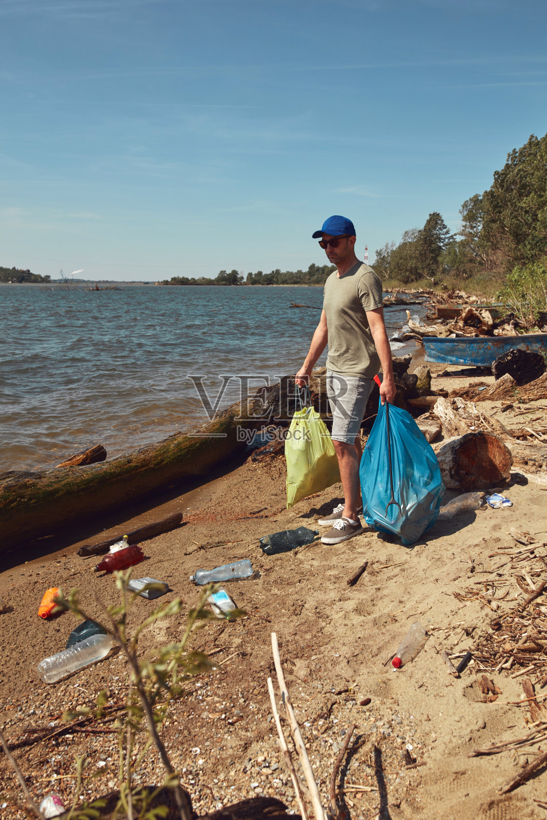 志愿者和环保人士正在清理堆满垃圾的肮脏河岸。照片摄影图片