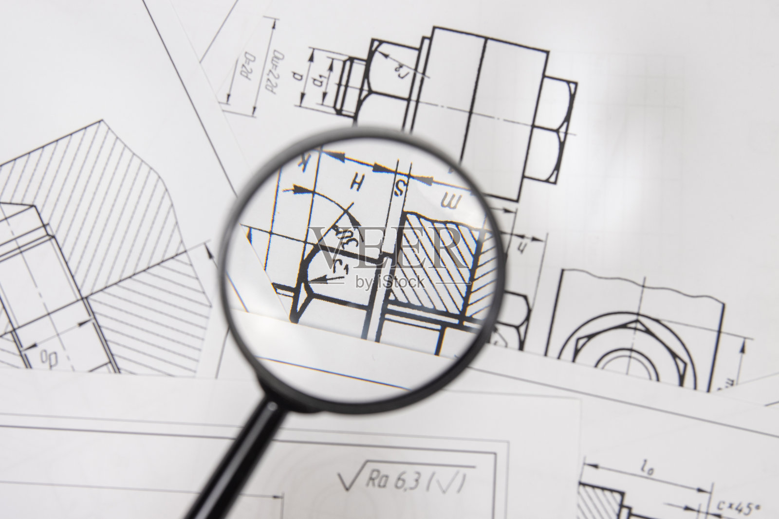通过放大镜绘制工业零件和机械的工程图照片摄影图片