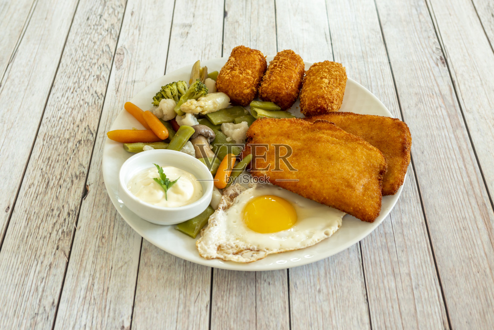 一盘美味的组合，有煮熟的蔬菜、炸丸子、涂了面包屑的鱼片、煎蛋和蛋黄酱照片摄影图片