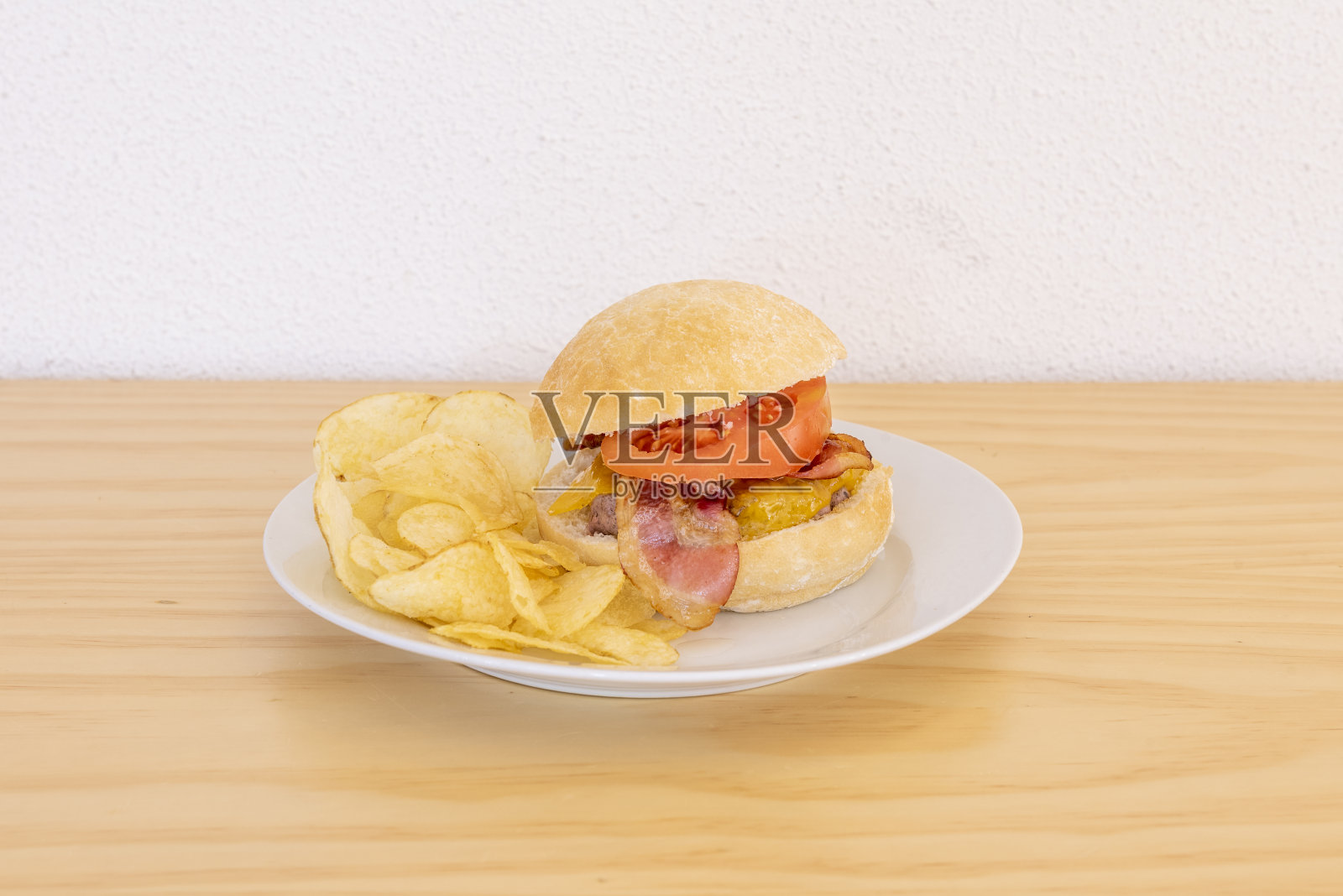 牛肉汉堡配烟熏培根，融化的切达奶酪，番茄片，乡村面包和炸薯条照片摄影图片