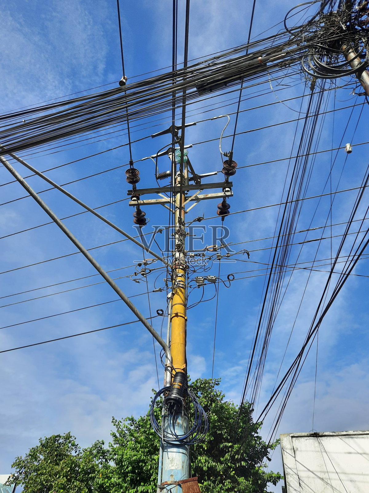 电力或电话网络电缆周围杂乱的支撑杆在蓝色的天空背景照片摄影图片