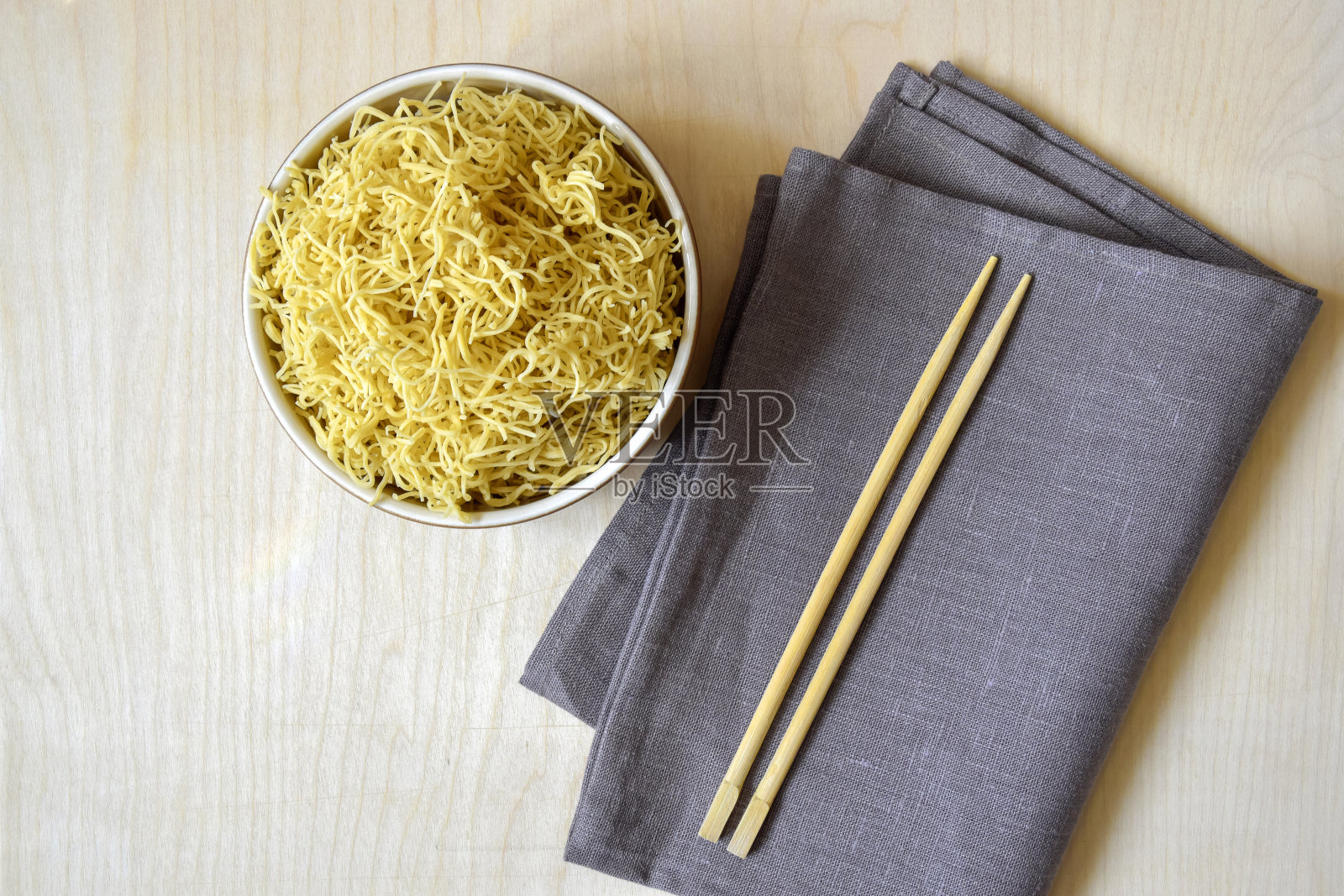 自制煮面，平铺。生意面在碗里。轻木表面主要成分、成品和一次性山毛榉木筷子。灰色的餐巾。前视图。照片摄影图片