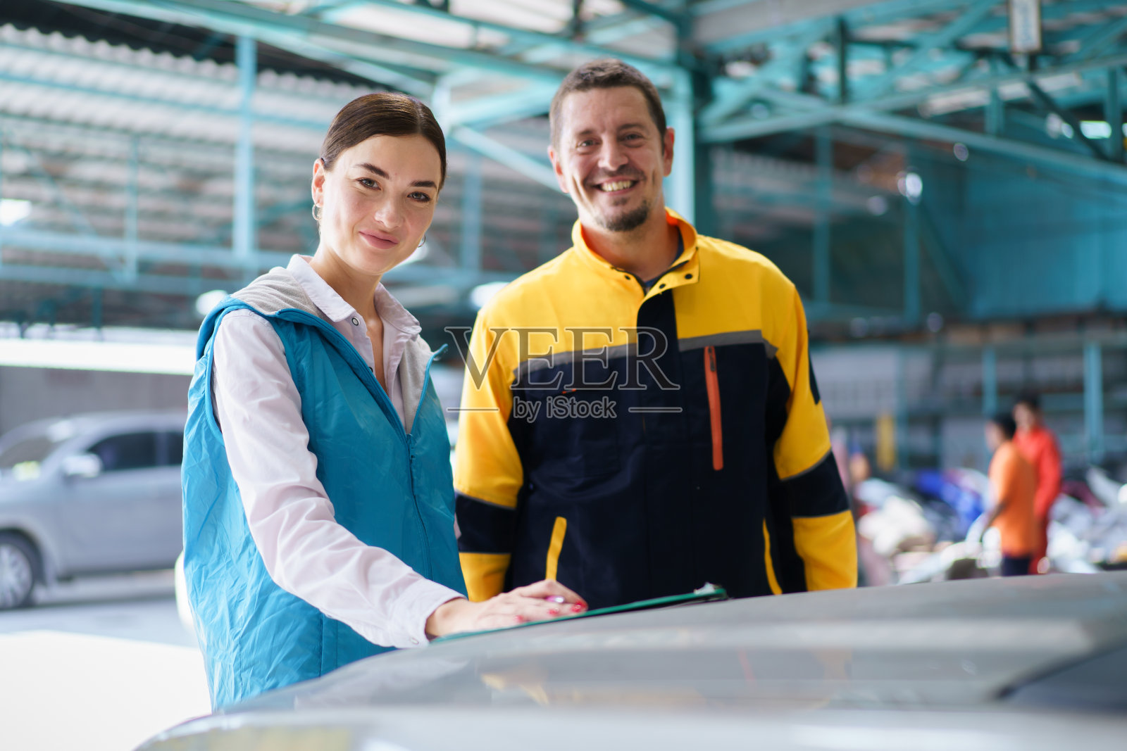 一名妇女和技术人员在车库里谈话。照片摄影图片