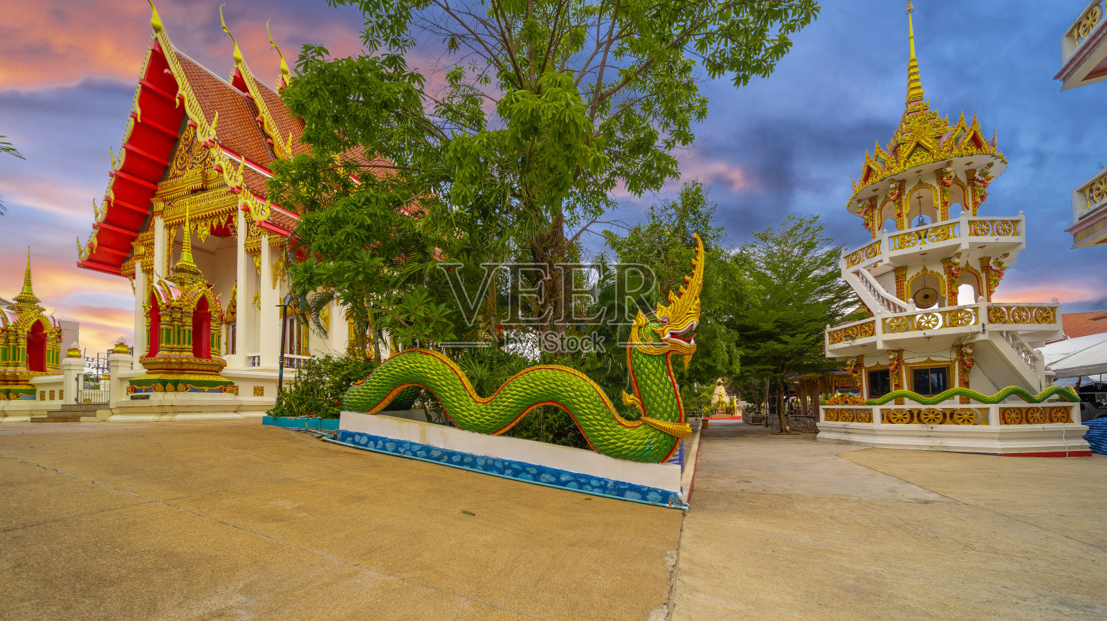 泰国普吉岛卡隆美丽的笏佛寺。以美丽华丽的金色、蓝色、绿色、红色和白色装饰。日落日出可爱的天空和云的颜色照片摄影图片