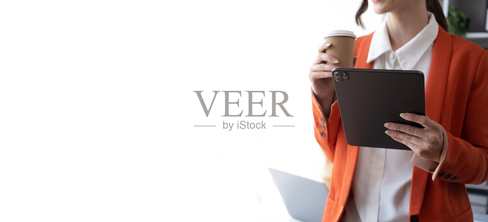 漂亮的白人白领一边喝着咖啡杯，一边在平板电脑上写字。照片摄影图片