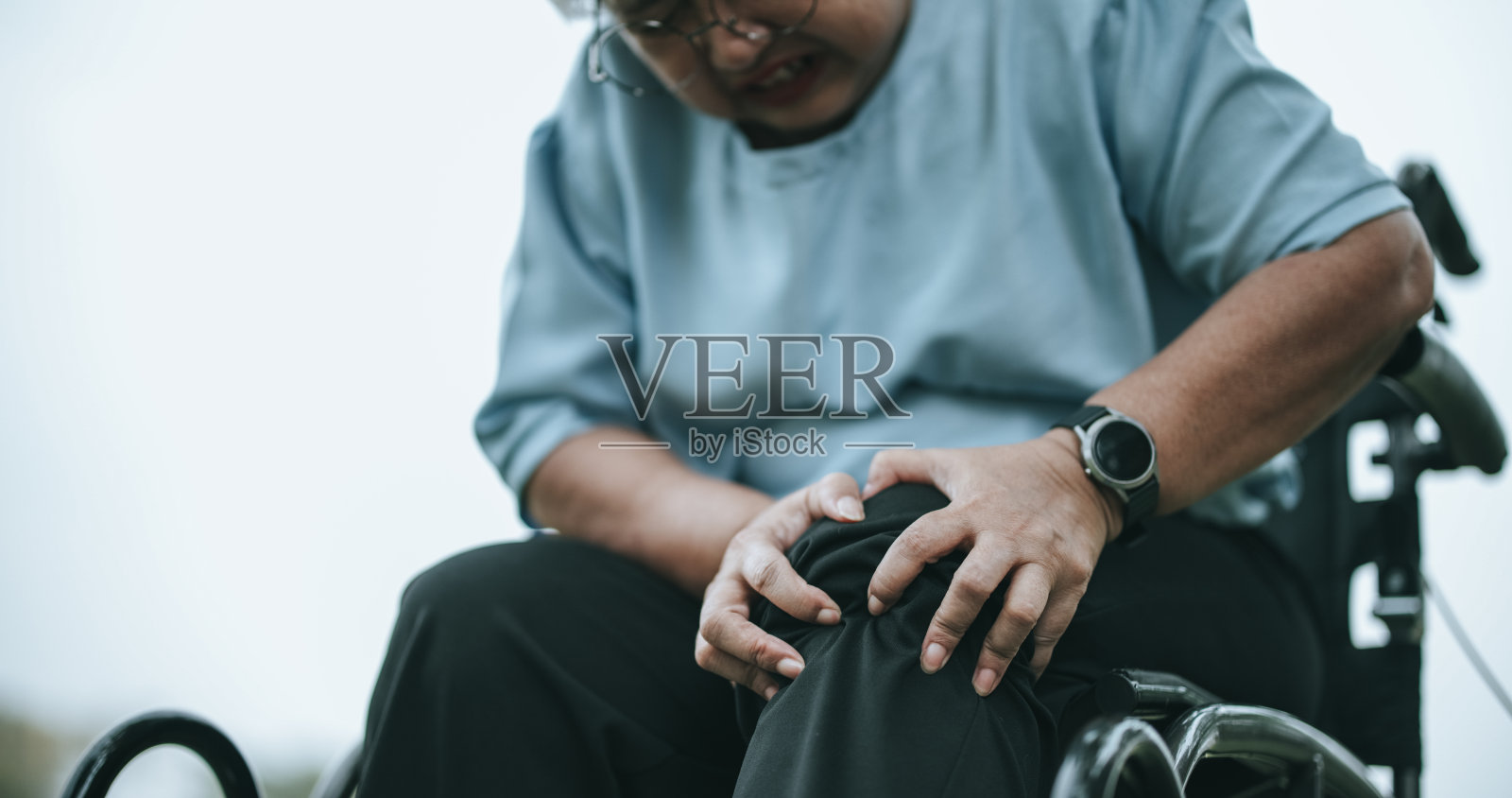 坐轮椅的成熟女性膝盖疼痛，脸上有疼痛的表情照片摄影图片