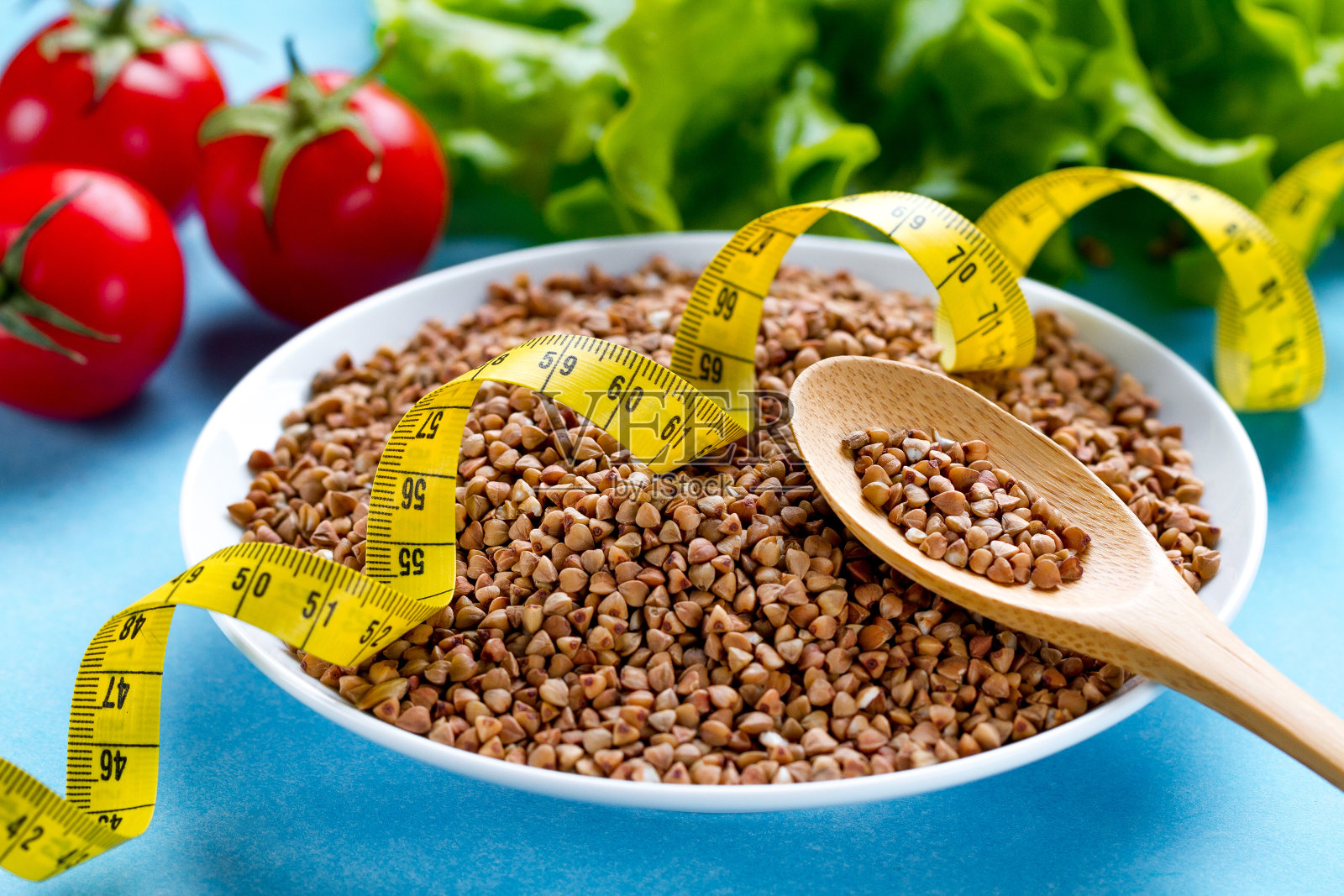 荞麦碗和勺子与新鲜成熟的蔬菜和黄色卷尺。荞麦为膳食谷物，健康饮食。纤维和减肥食物。饮食概念照片摄影图片