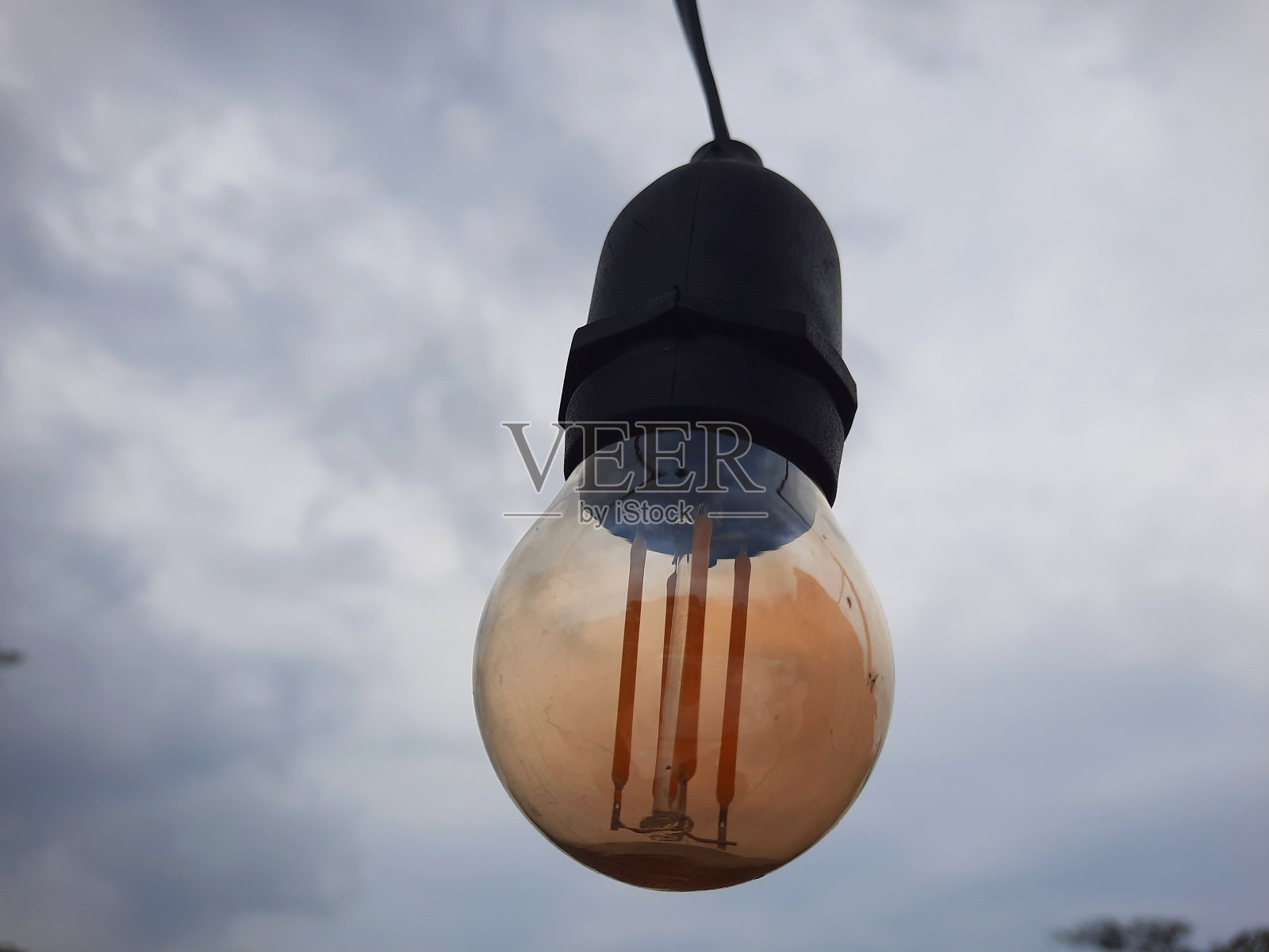 在多云的天空背景下，花园里的灯泡或灯光照片摄影图片