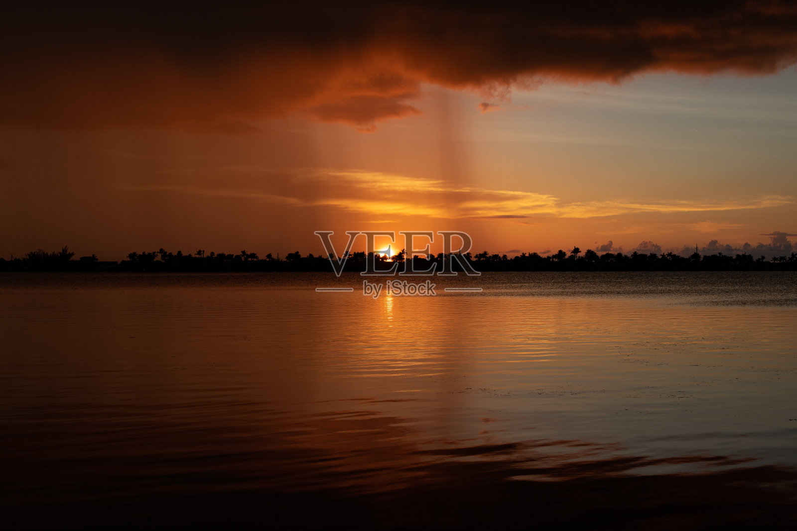 热带倾盆大雨下，海上美丽的日落照片摄影图片