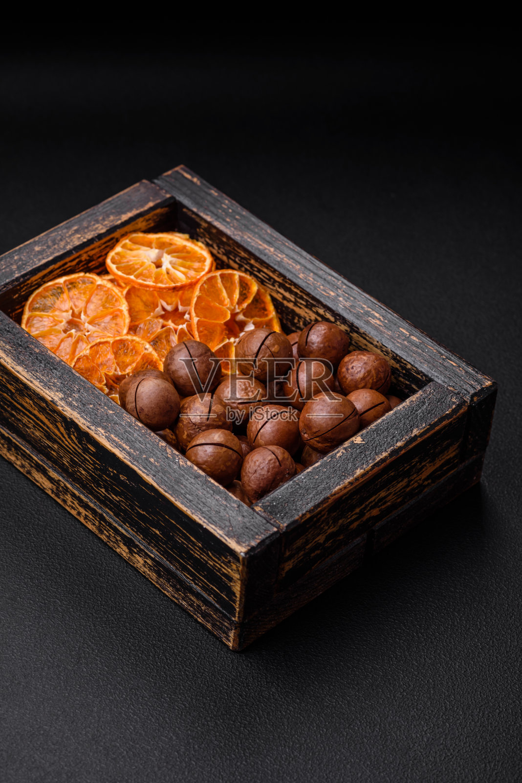 美味的烤夏威夷坚果壳在黑色纹理的背景照片摄影图片