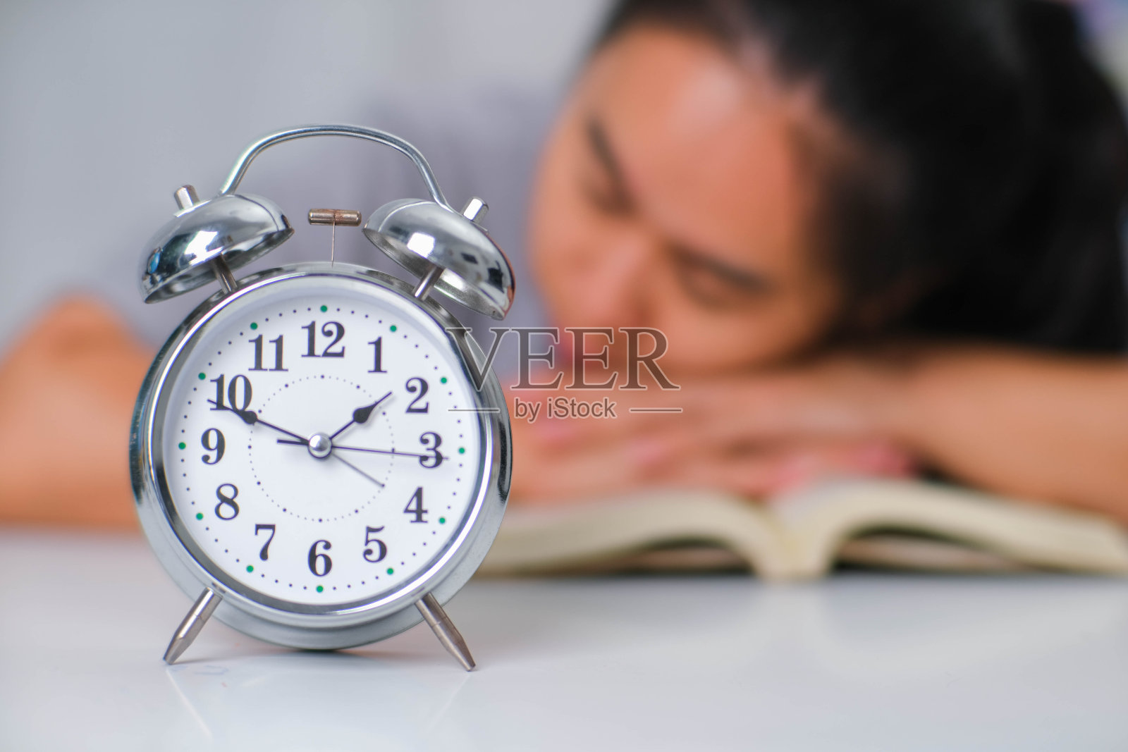 疲惫的亚洲女人坐在书桌前在客厅看书。照片摄影图片