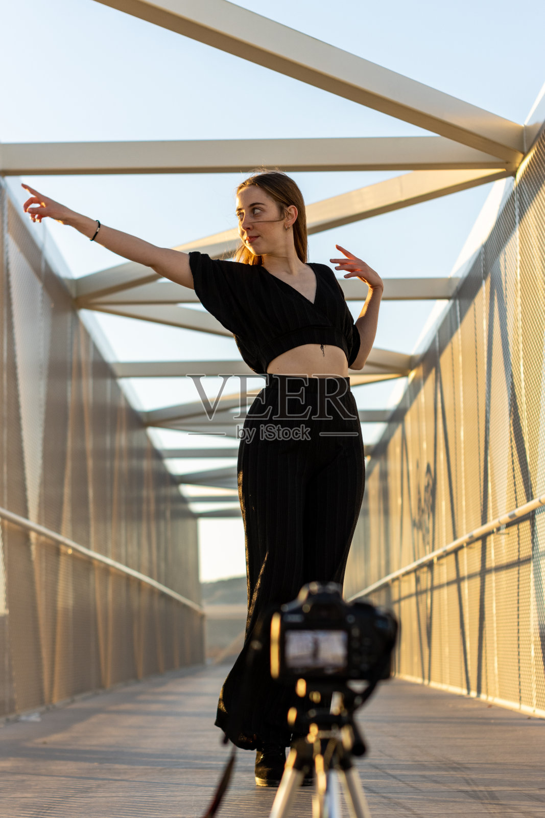 一个年轻的金发白人女子在户外用相机拍摄舞蹈课的垂直肖像。快乐的节奏照片摄影图片