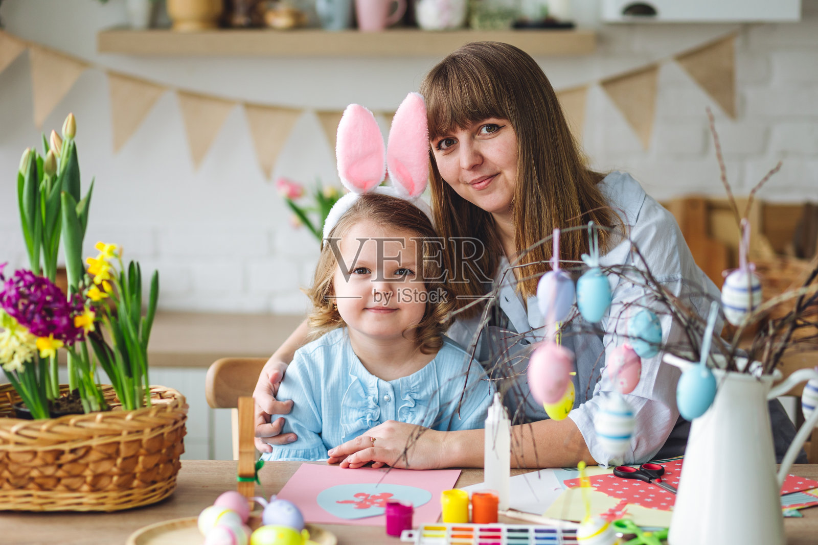妈妈和女儿一起画彩蛋，创造家里复活节的装饰，开心、欢快。可爱漂亮的微笑小女孩，家庭时光。清新的春天，厨房里鲜艳的花朵。阳光灿烂的日子照片摄影图片