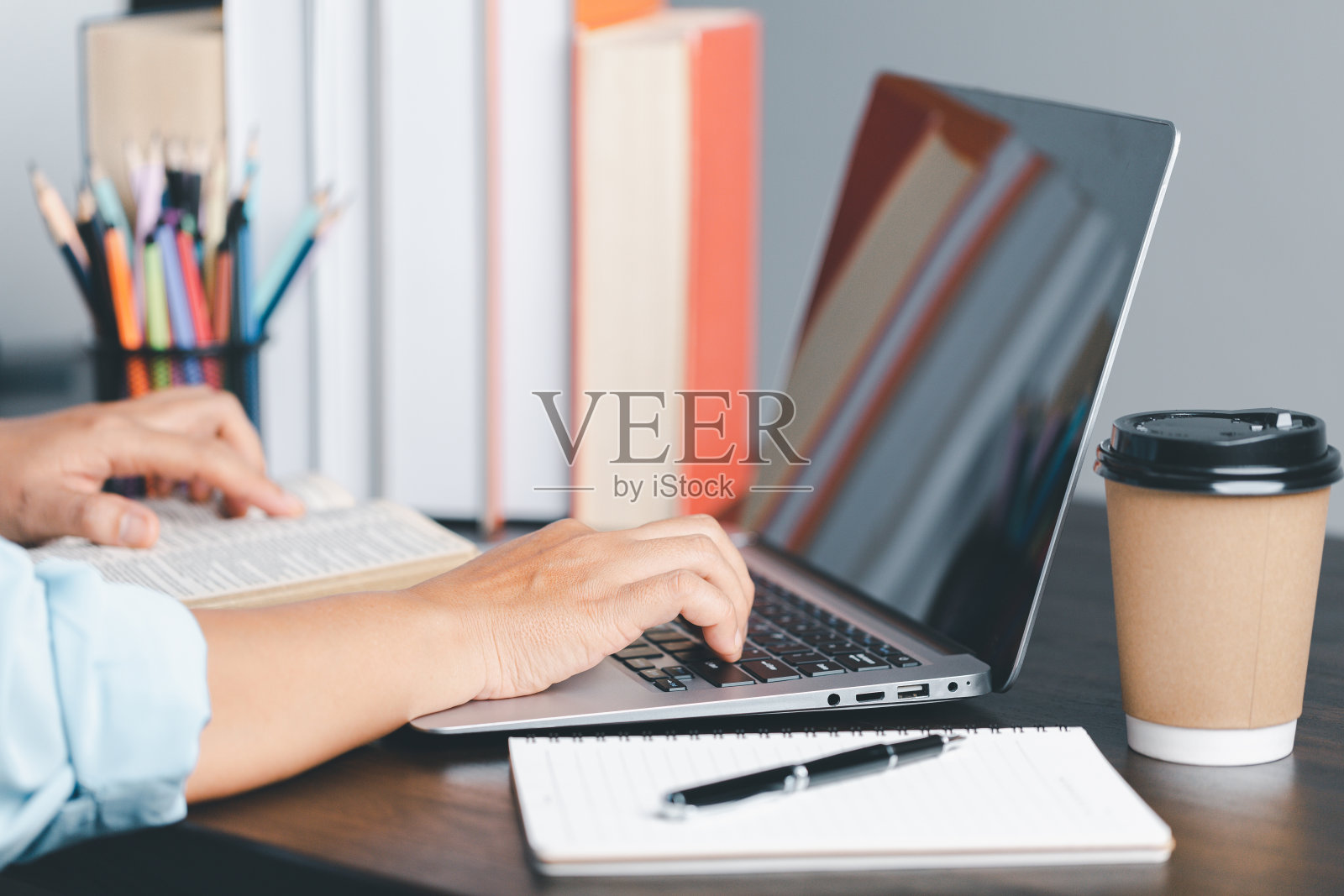 教育的概念。女学生近距离在笔记本电脑上做笔记，手打字，在家用电脑上网学习。女人在电脑上打字，通过网络摄像头远距离通话，在笔记本电脑上进行虚拟变焦通话。照片摄影图片