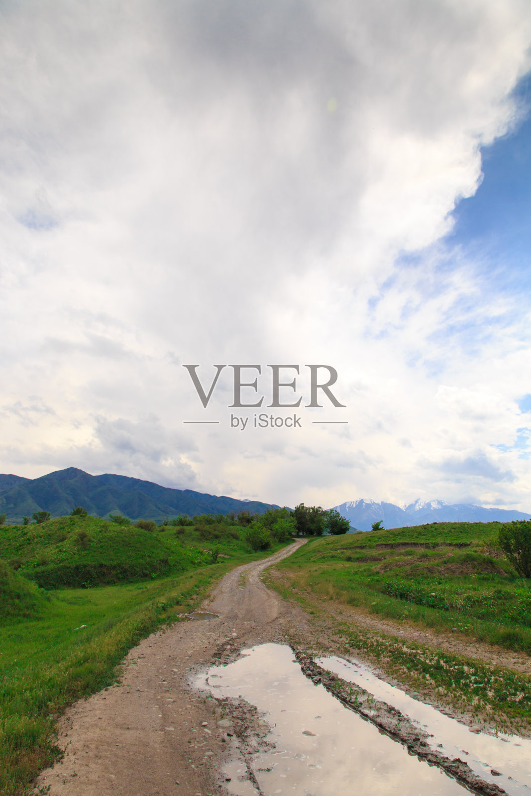 美丽的春夏景观。青山之间的乡间山路。青山葱翠，高山高耸。夏天的自然背景。照片摄影图片