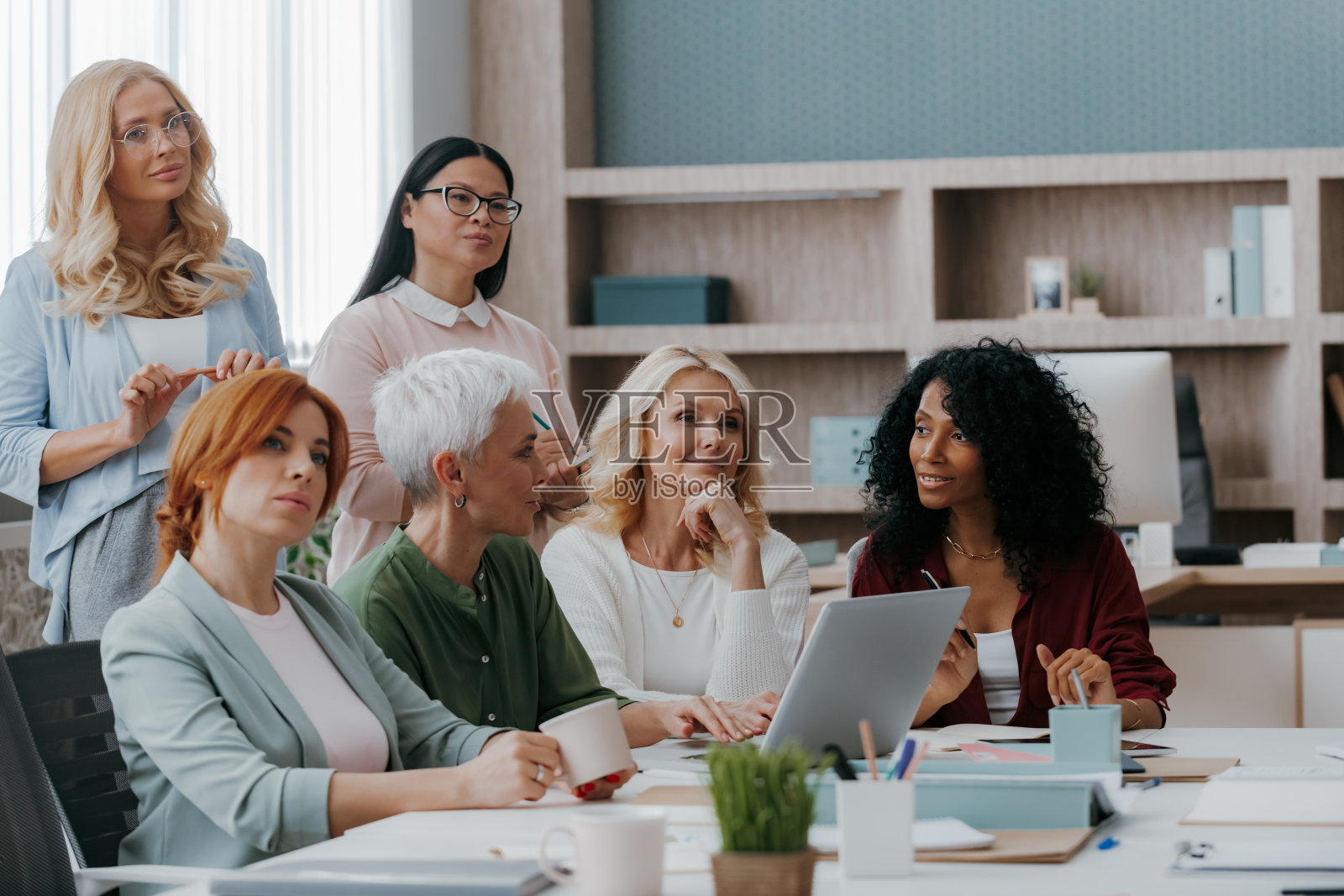 一群成熟的女性一边听演讲者一边在办公室接受业务培训照片摄影图片