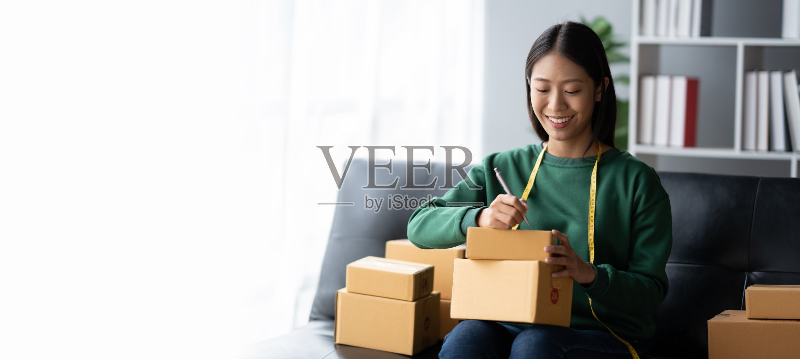 可爱的亚洲企业主在分发给客户之前，在包裹盒上写下客户的详细信息。照片摄影图片