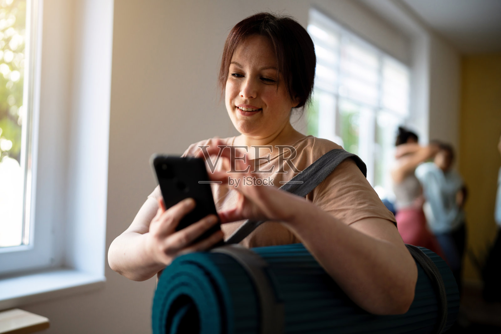 瑜伽课后用手机的女人照片摄影图片