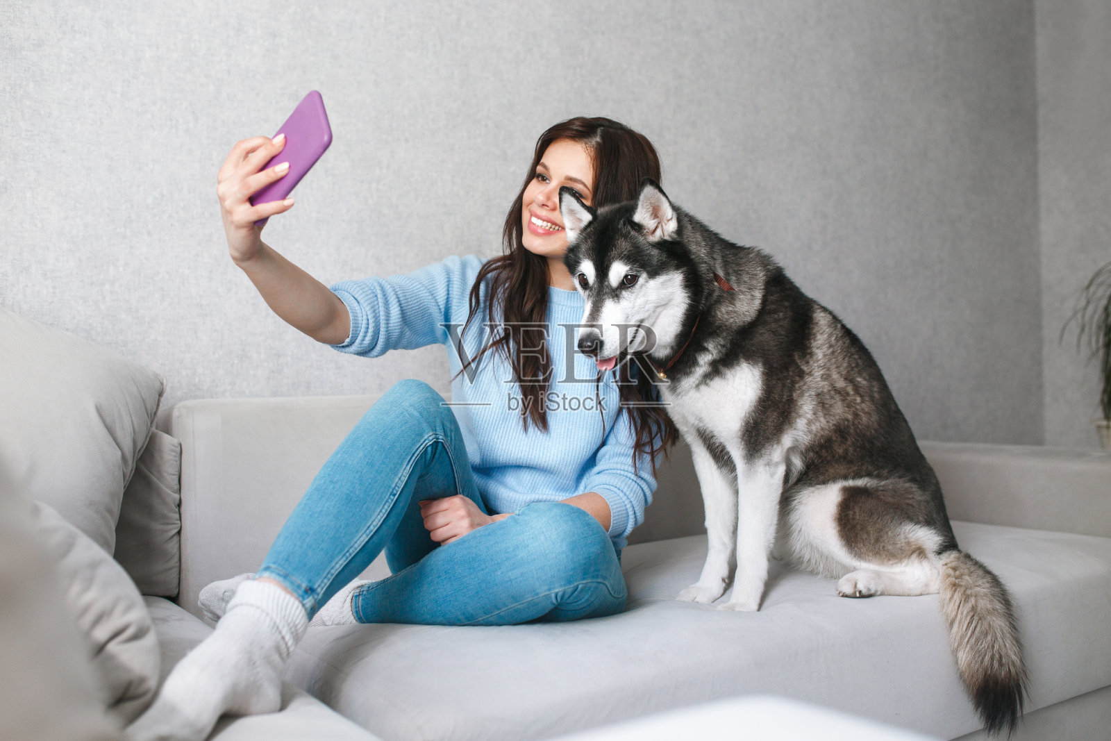 快乐的年轻女子在家里和哈士奇狗自拍照片摄影图片