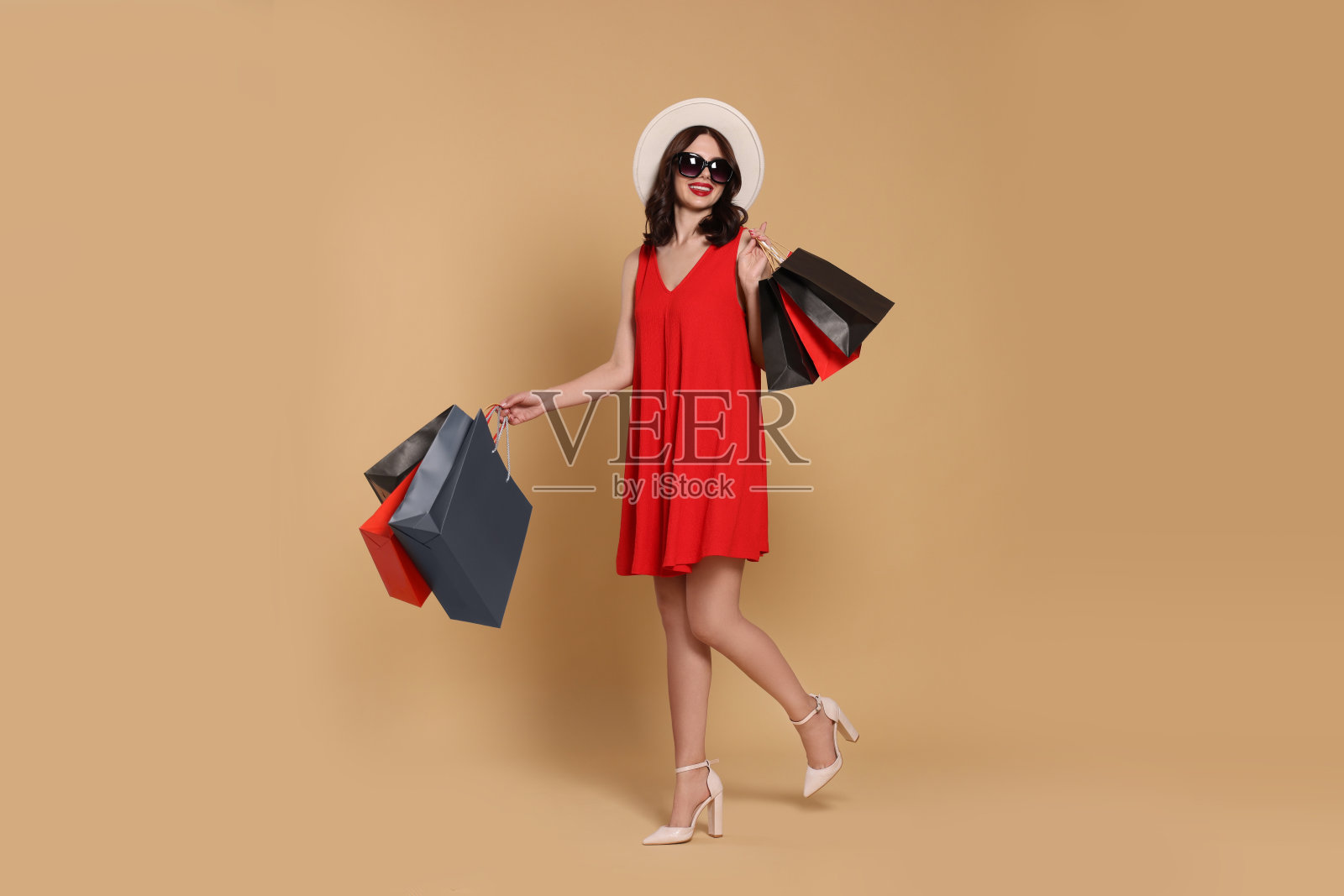 漂亮的年轻女子拿着米色背景的购物袋照片摄影图片