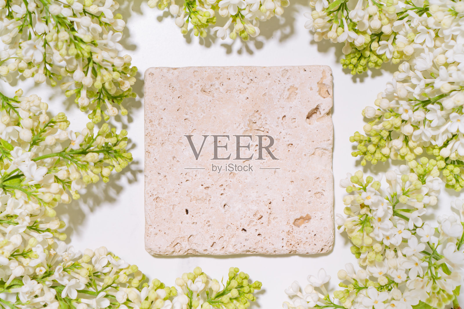 化妆品护肤品展示用石制讲台和丁香花枝制作的平铺模型场景。摄影工作室。照片摄影图片