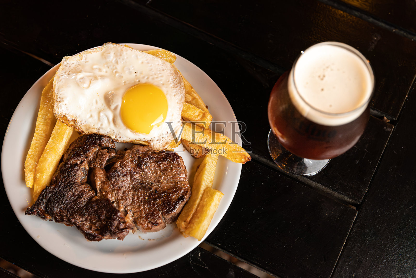 餐厅里的烤牛肉配煎蛋和一杯啤酒照片摄影图片