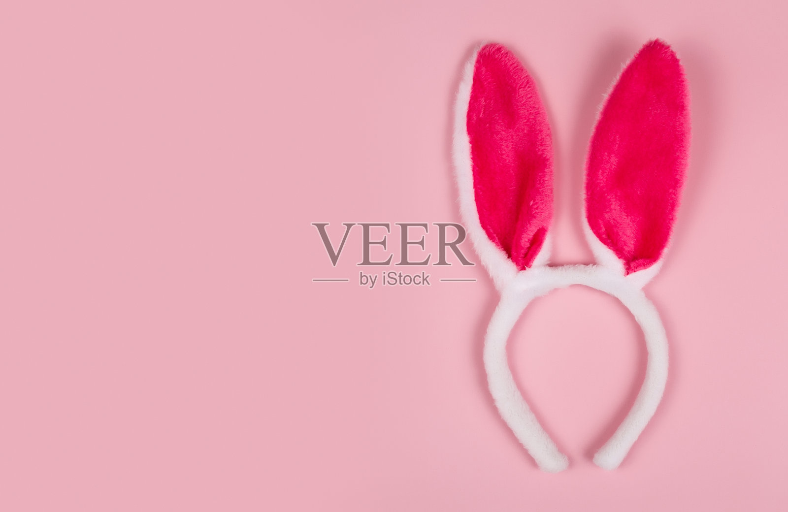 贺卡与兔子耳朵在粉红色的背景。复活节快乐。本空间照片摄影图片