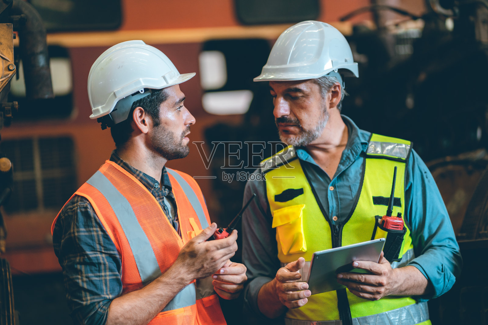 2名土木工程师或专业领班，头戴安全帽，手拿图纸，手拿数码平板电脑，站在工业工厂工作，团队合作理念照片摄影图片