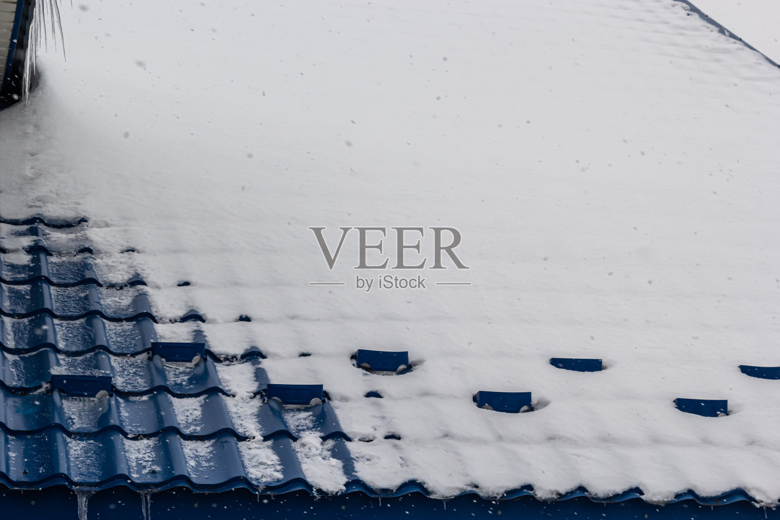 雪落在一座欧洲房子的红棕色金属瓦屋顶上照片摄影图片