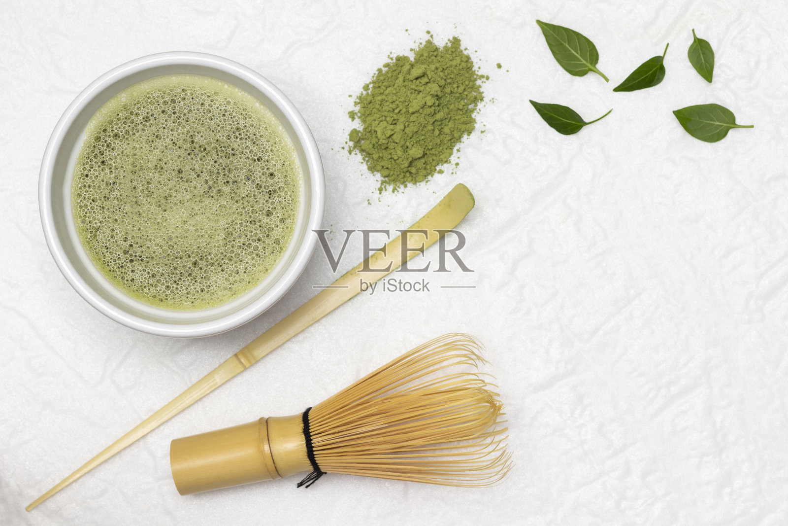 碗里的抹茶绿茶。制作抹茶绿茶用的竹制打蛋器和竹制量匙。照片摄影图片