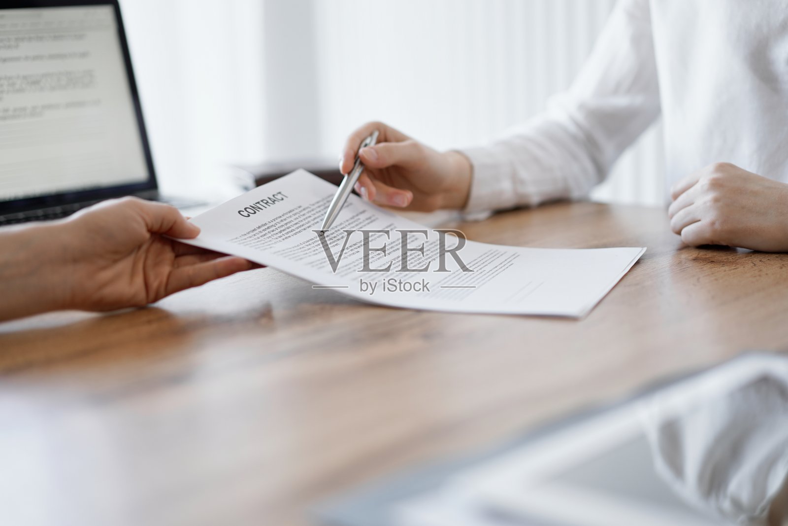 女商人律师指着合同的特别点，在办公室的木制办公桌前为同事或客户承认一些事情。商务人士的团队合作和伙伴关系，会议理念照片摄影图片